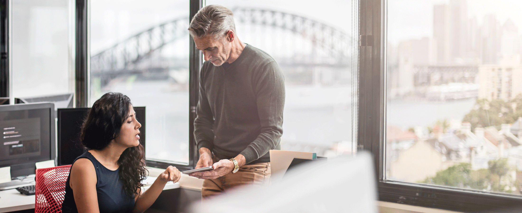 man and woman discussing in office with sydney harbour bridge in background