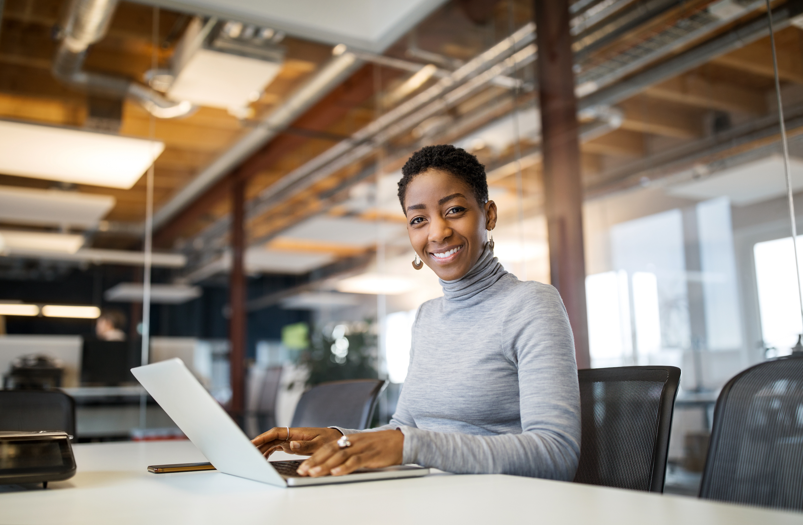 Woman smiling using laptop in business setting