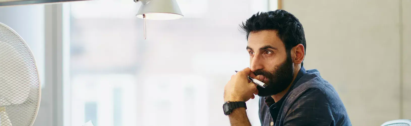 Person holds pen in hand up to his chin while considering how microlearning can enhance compliance and ethics training programs.