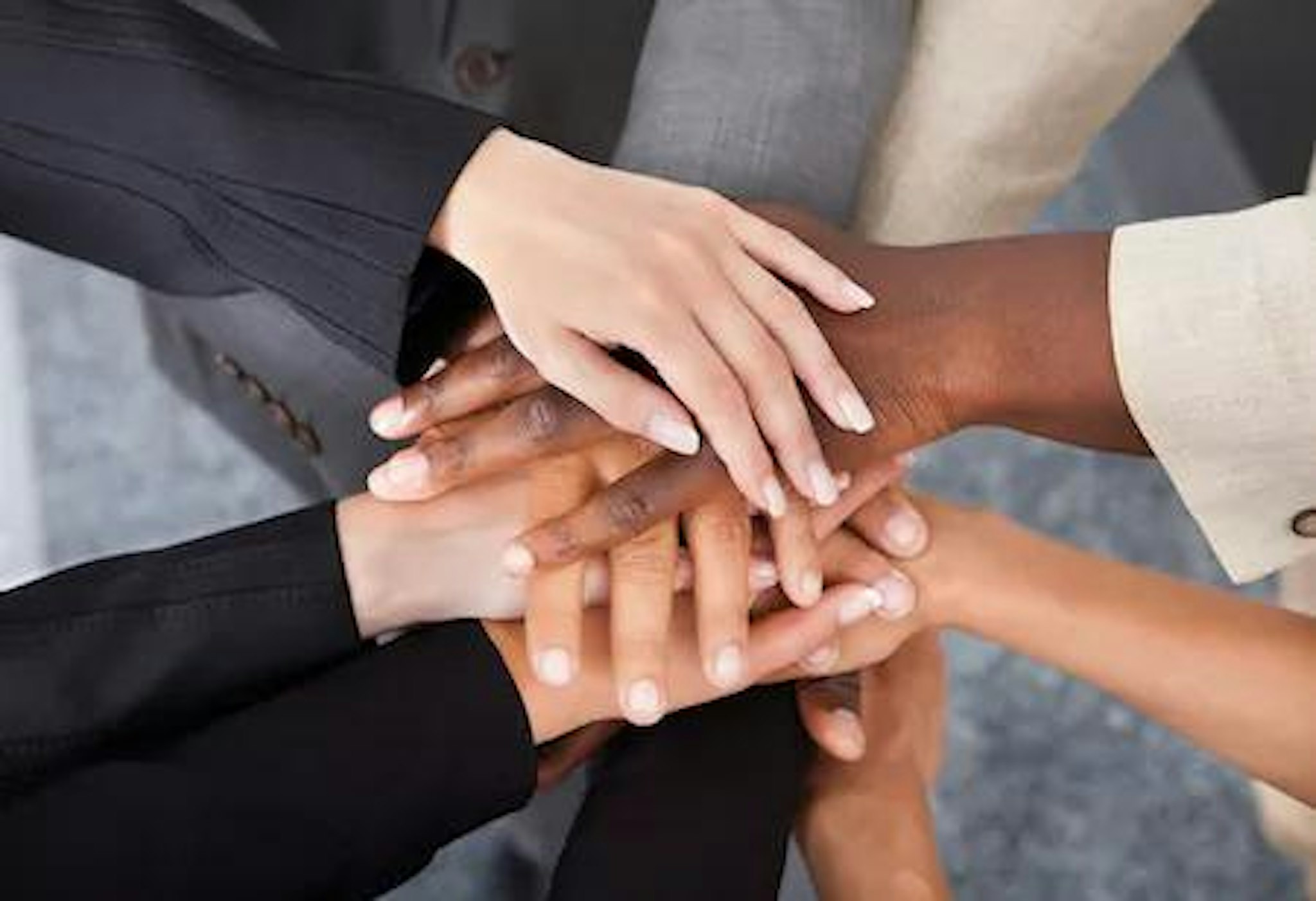 Numerous hands come together in center of image to represent diversity and teamwork, two aspects of creating a healthy board culture.