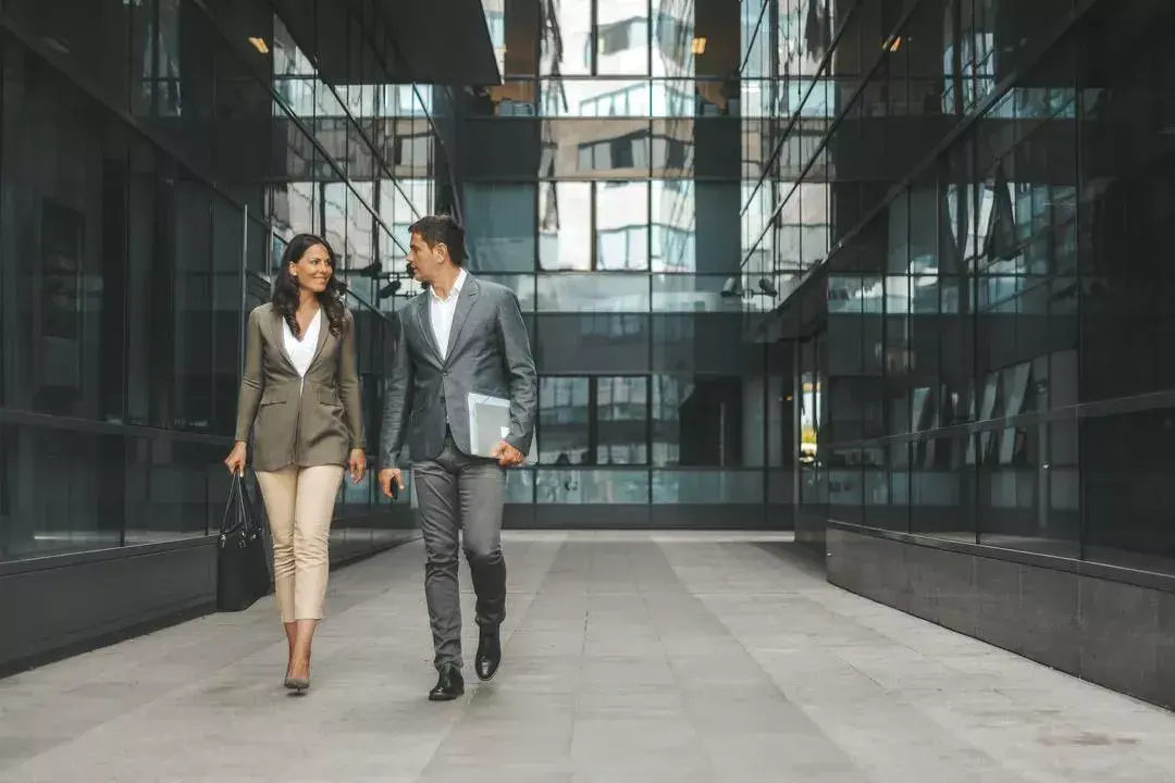 Man and woman in business attire walk through an office hallway together discussing cyber threats