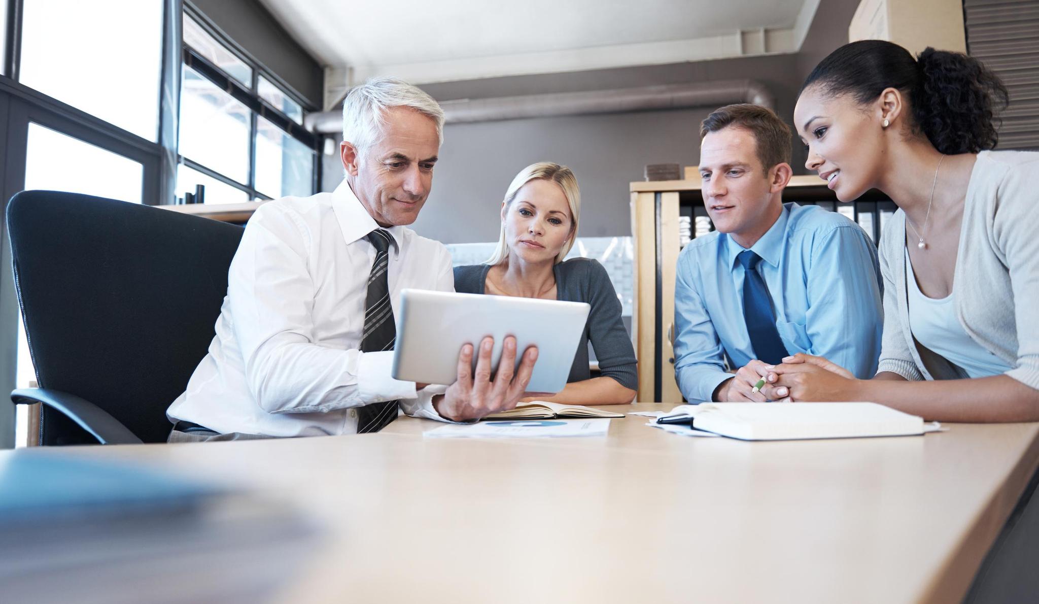 Group reviewing tablet to see how their board meeting minutes should be formatted