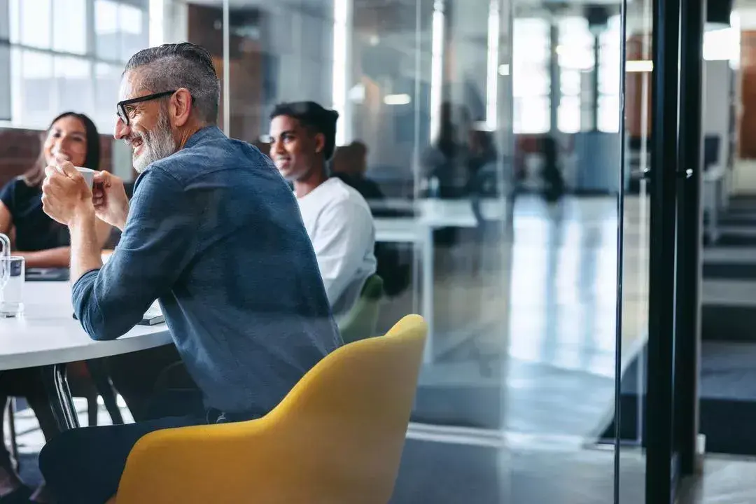 Three people sit in an office around a table, having a conversation about software vendor consolidation