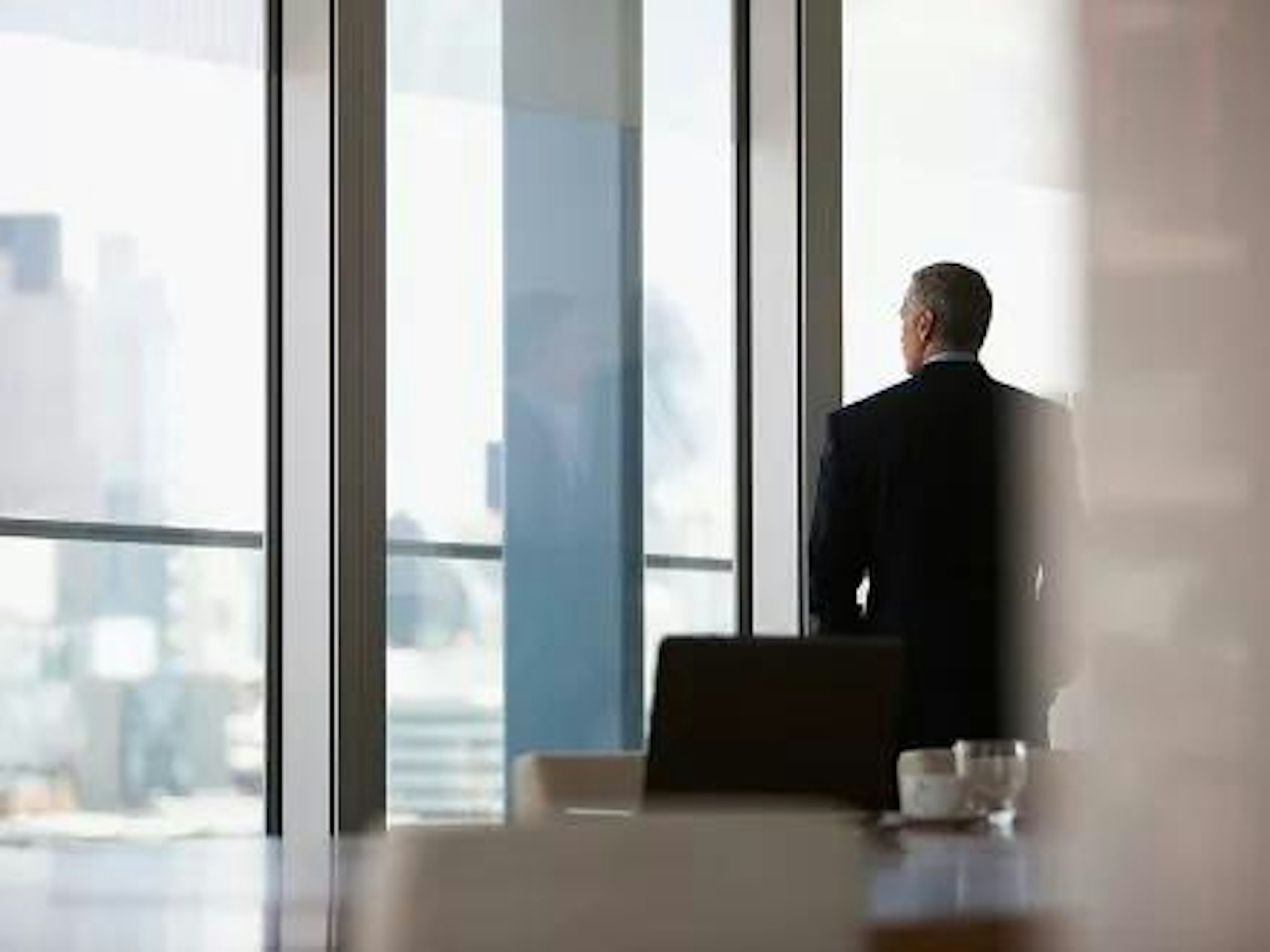 Board member considers business ethics and corporate social responsibility while looking outside boardroom window