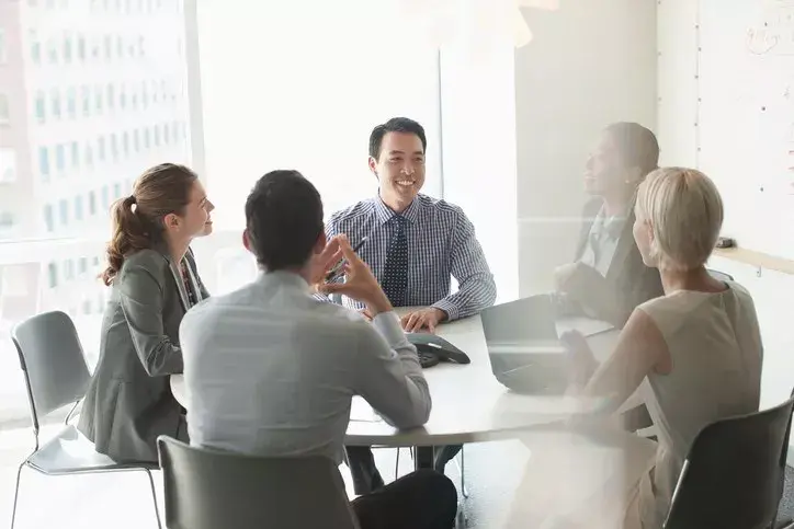 People sat around table illustrating being part of a holding company