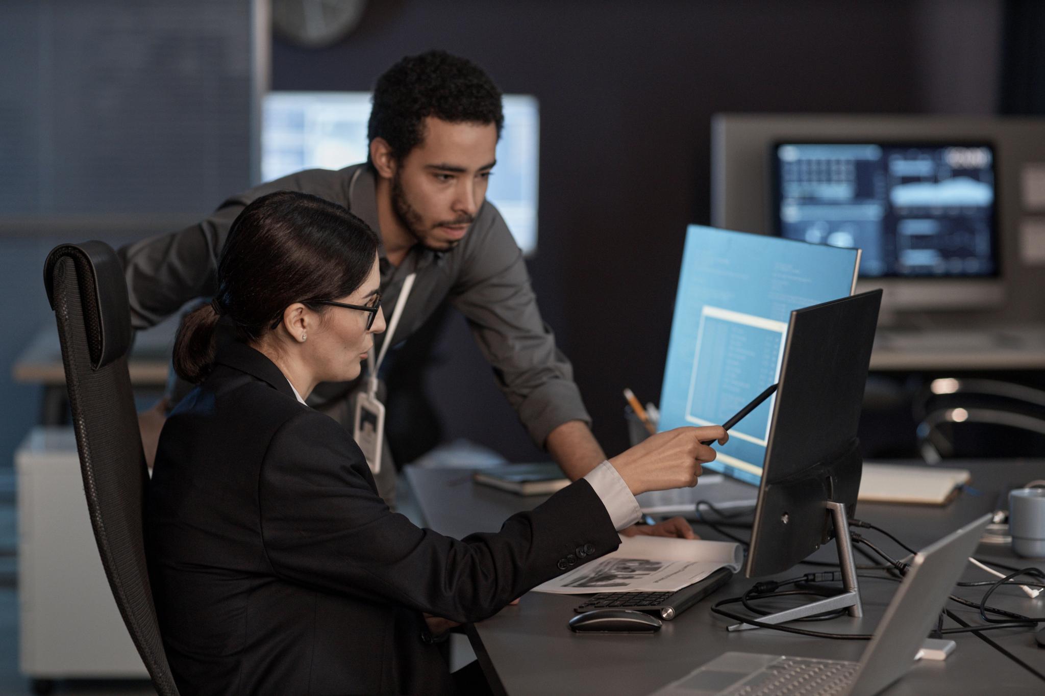 two officers workers pointing at a computer screen