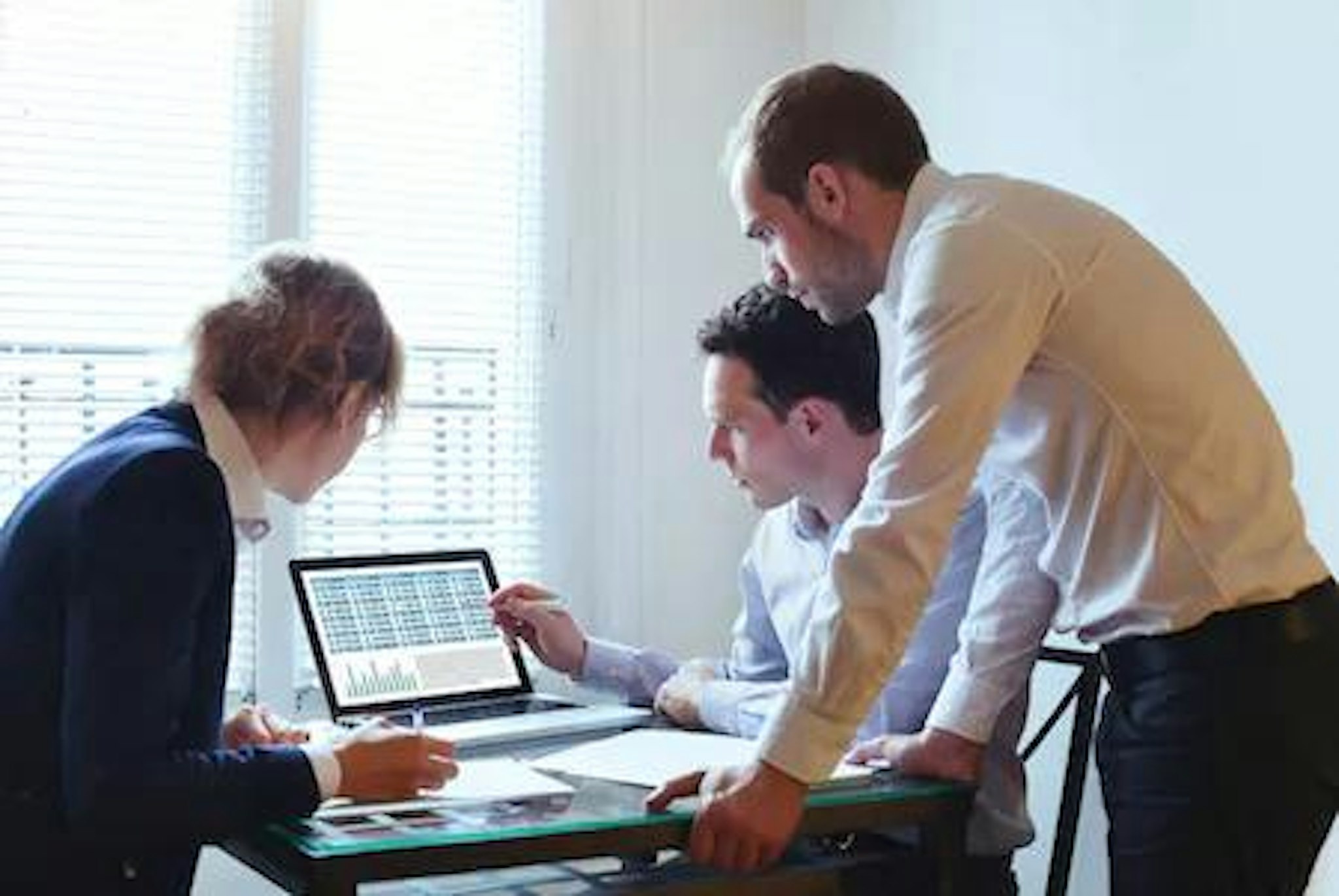 People surrounding a laptop to review the difference between purpose-built entity management software and Microsoft Excel