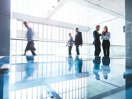 Professionals walk through office building while two colleagues hold the BCP and make adjustments to it.