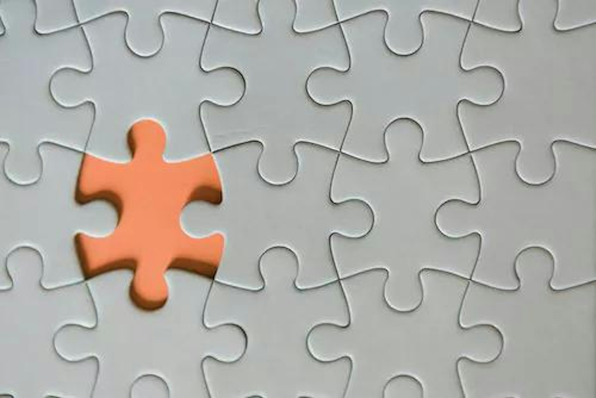 Picture of a grey puzzle with one orange piece