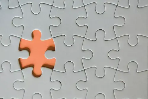 Picture of a grey puzzle with one orange piece