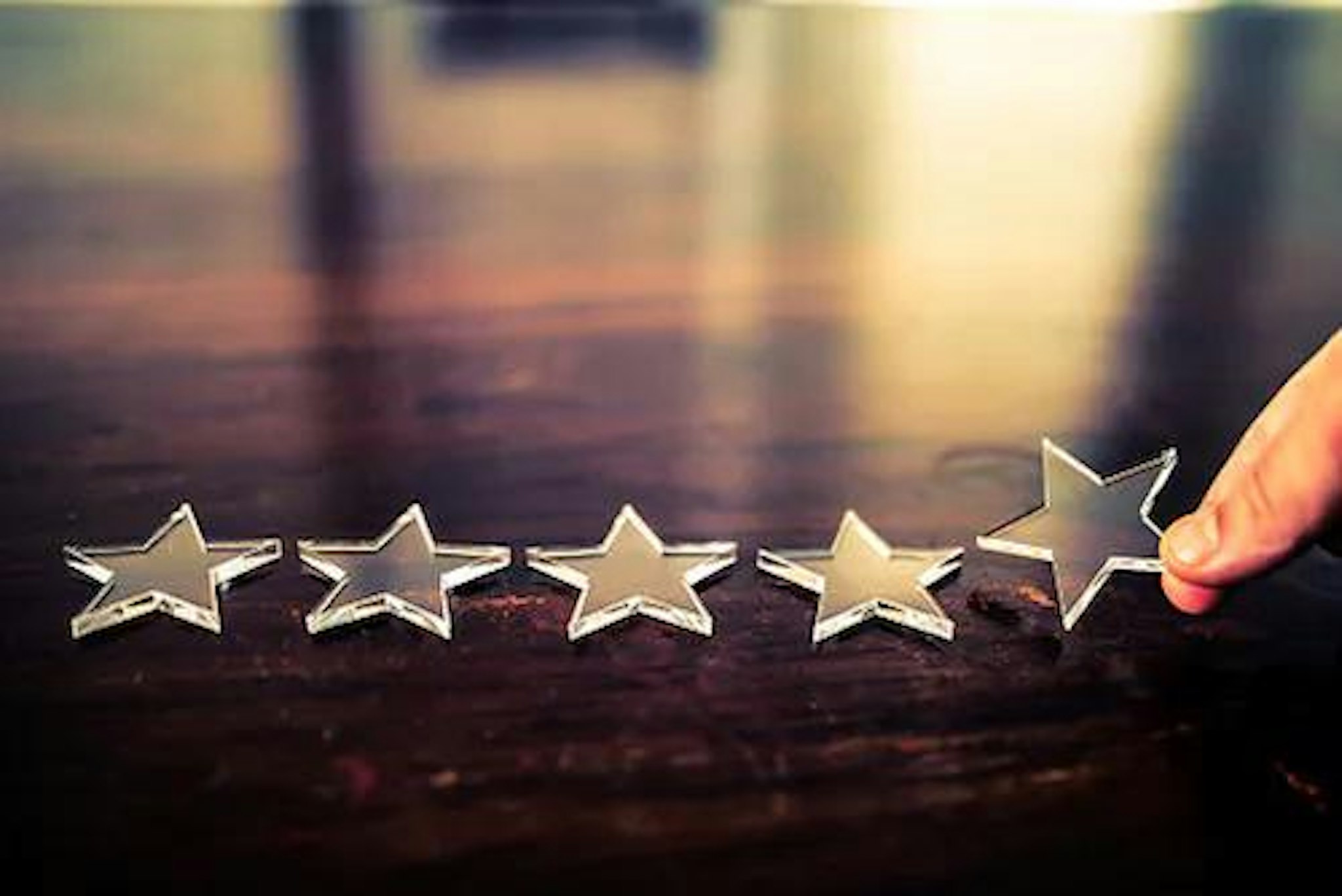 Image of person placing 5 stars on the table representing ratings