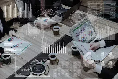 Picture of desk with people working with documents. Various semi-transparent charts are overlaid across the image. Image representing the benefits of having esignatures within entity management software.