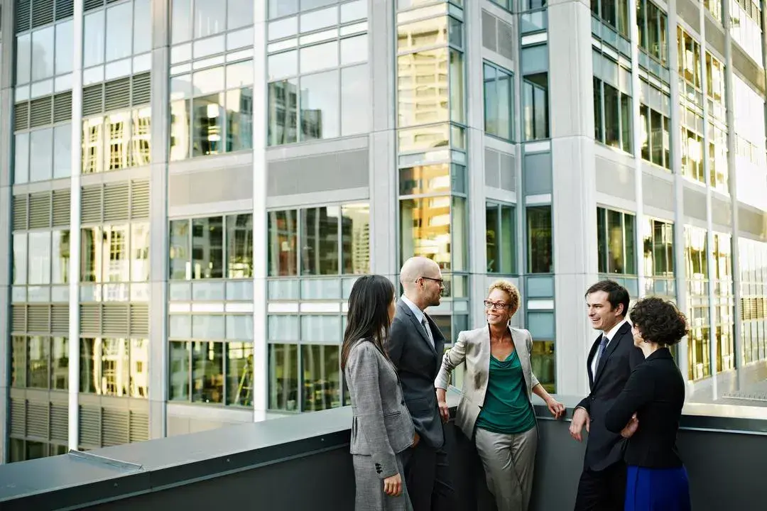 Group of people stand outside their office, discussing how to lead cyber culture