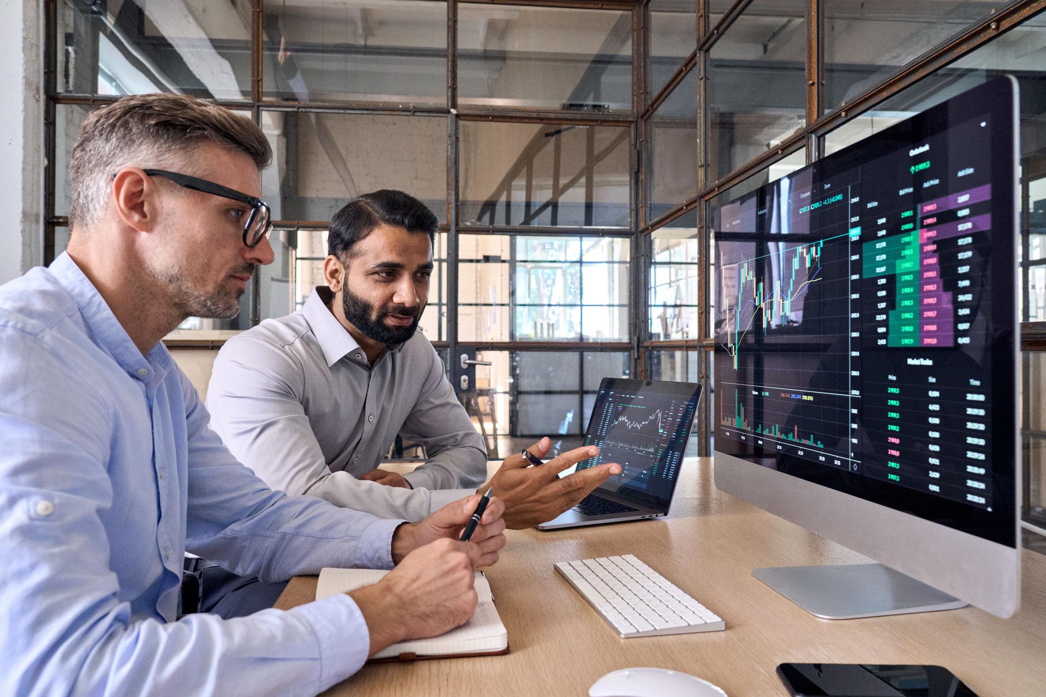 Businessmen looking at charts on a monitor