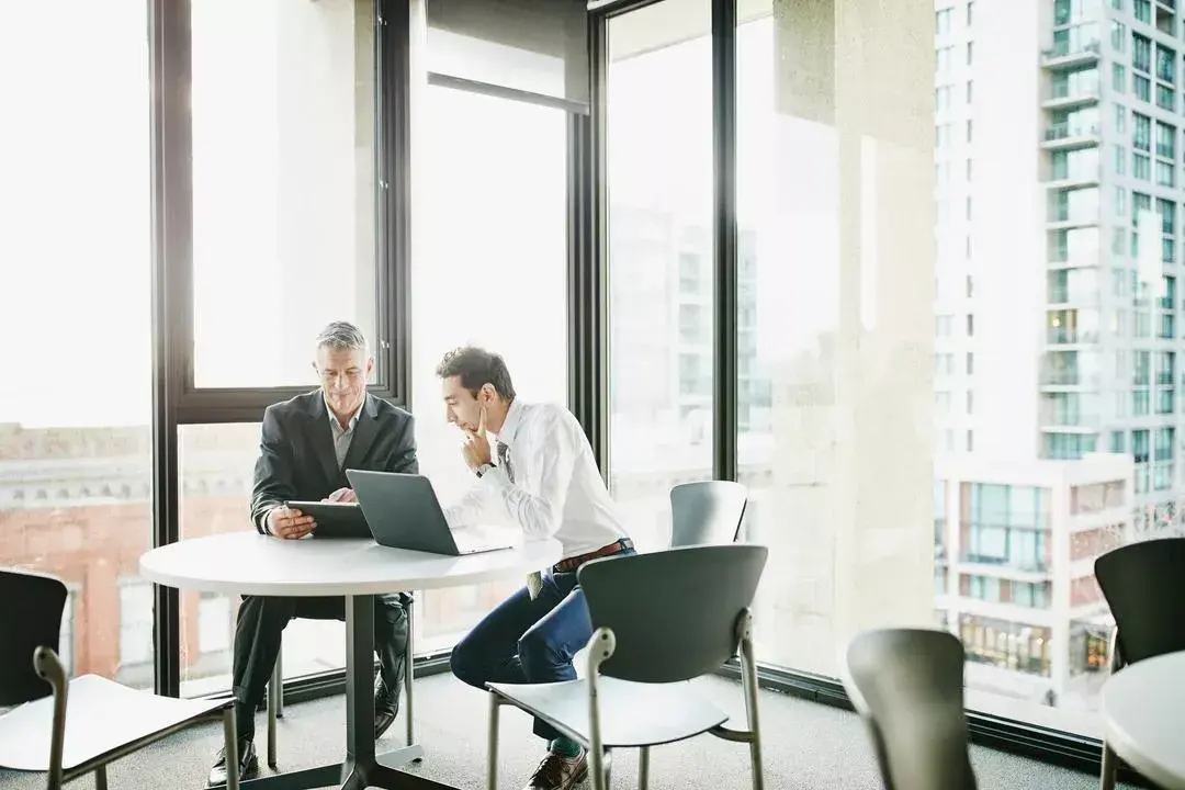 Two men sit in an office evaluating the costs of cutting board management software