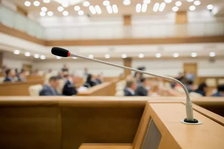 Council meeting with image focus on the microphone and blurred people in the background.