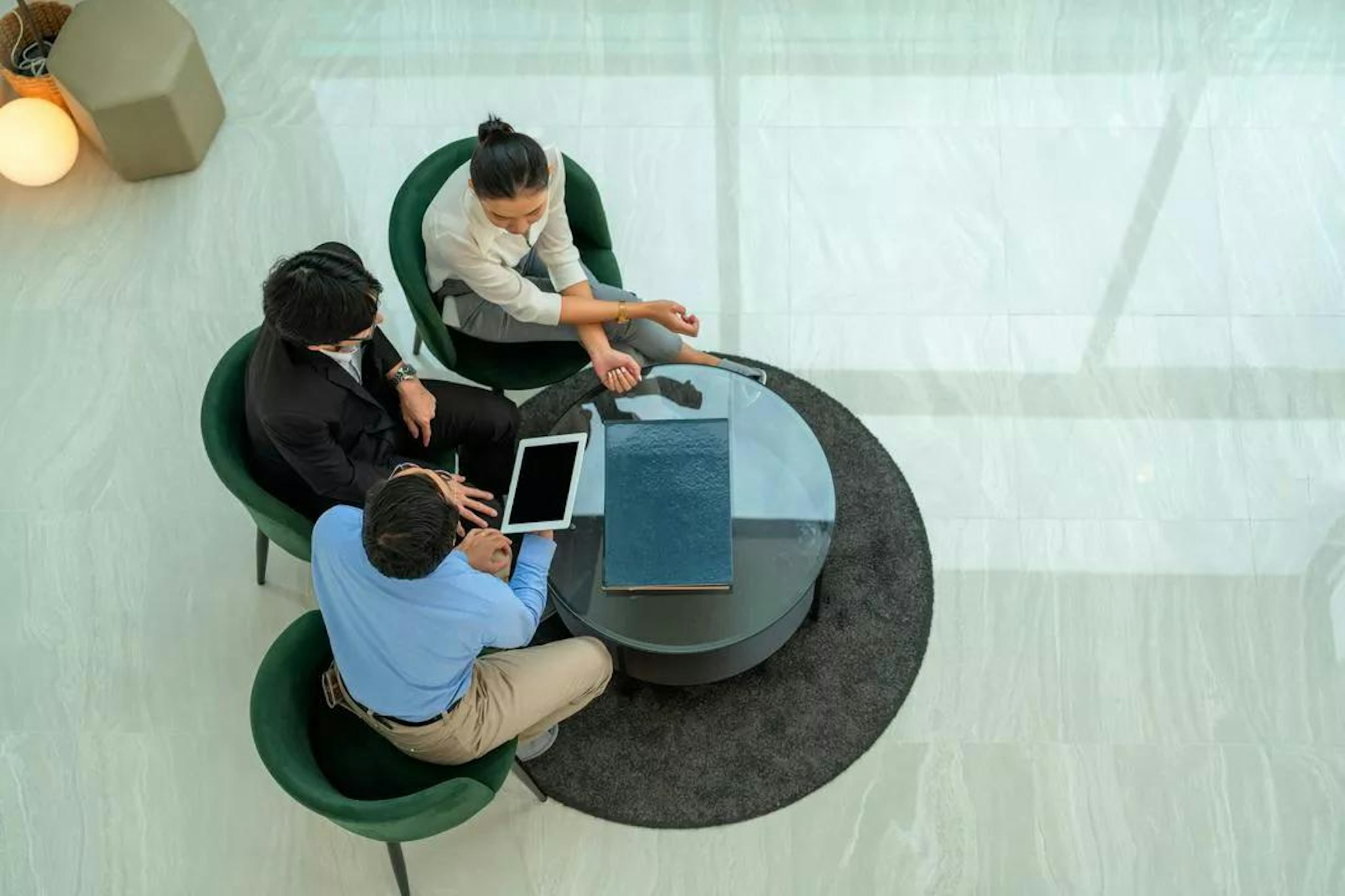 An overhead view of three people sitting around a table in an office, discussing GRC tech integration